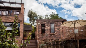 A brick building with a pool, outdoor seating, and a satellite dish. - Jenny's Guest House (Makhanda)