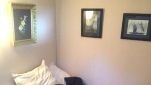 A single bed with a white and red blanket, a black pillow, and a beige wall with three framed pictures. - Diamond in the Bluff (Pointe-du-Chene)
