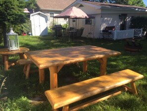 Une table de pique-nique en bois avec des bancs, située dans un jardin.