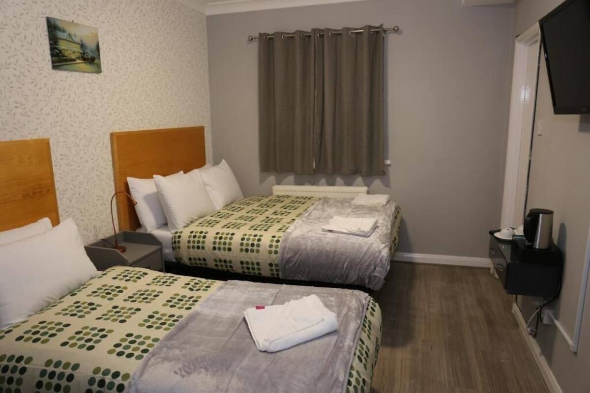 A hotel room with two beds, a TV, and a small table with a coffee maker.
