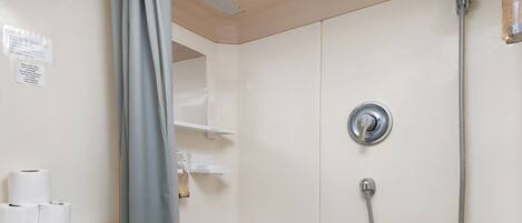 A bathroom with a sink, toilet, and shower. There are toilet paper rolls on the counter.