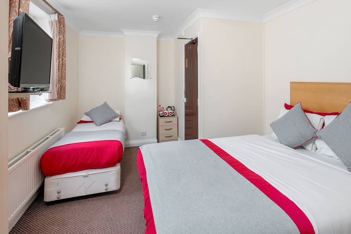 A hotel room with two beds, a television, a mirror, and a wardrobe.