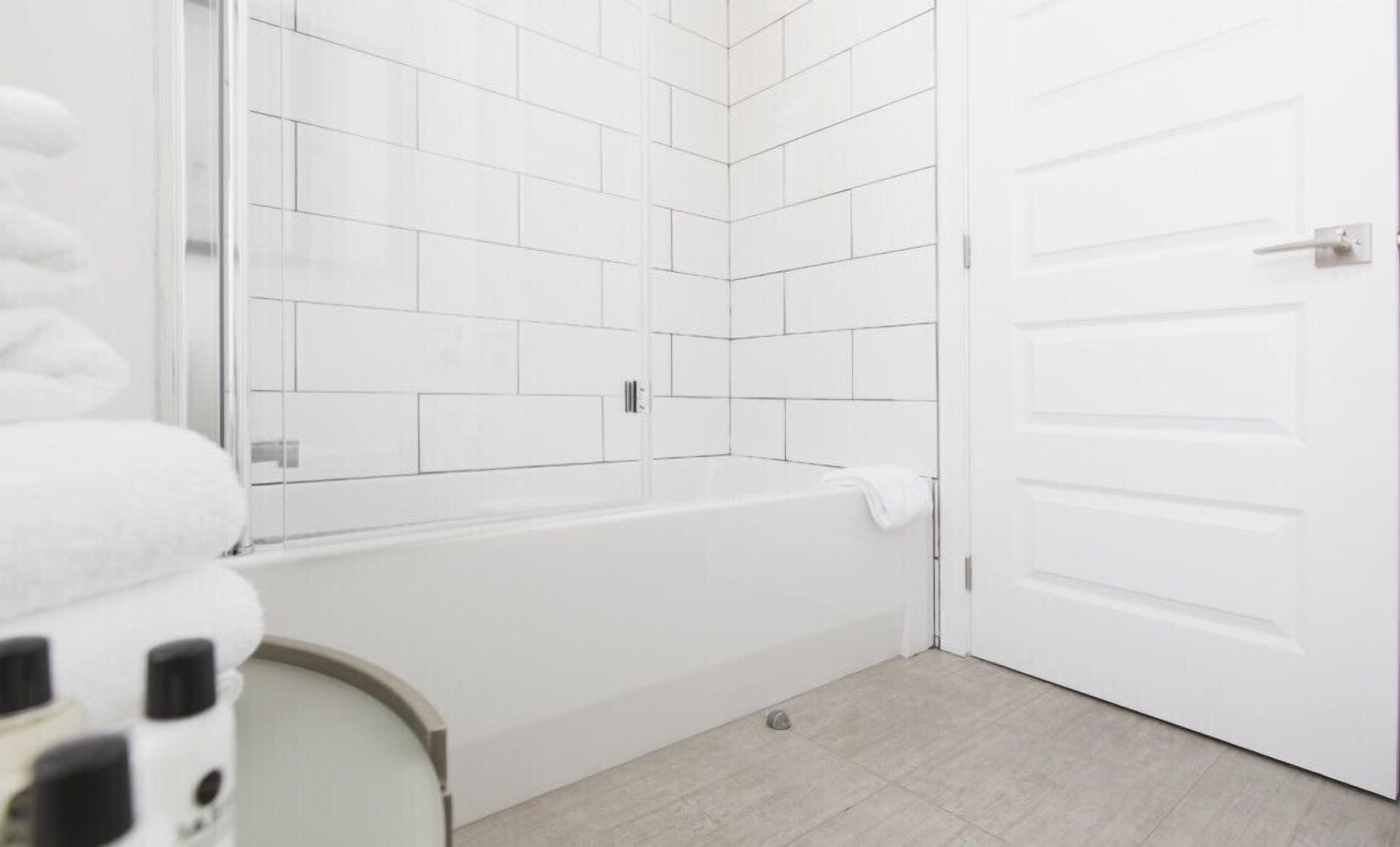 A bathroom with a white bathtub, a white door, and a tiled shower area.