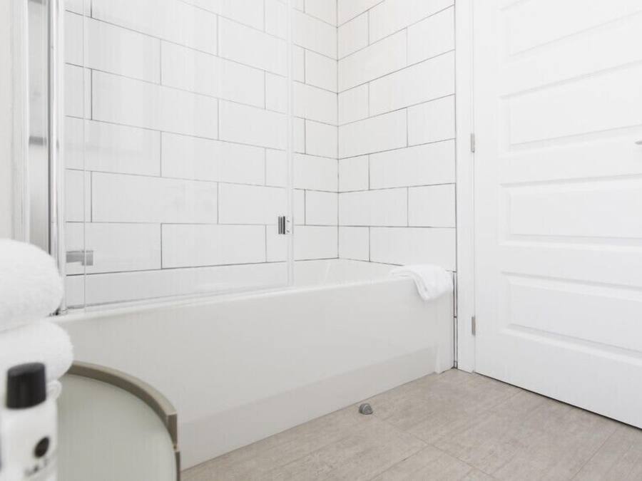 A bathroom with a white bathtub, a white door, and a tiled shower area.