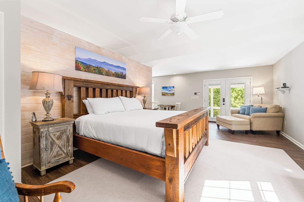 A bedroom with a wooden bed, a nightstand, a dresser, a chair, and a sofa.
