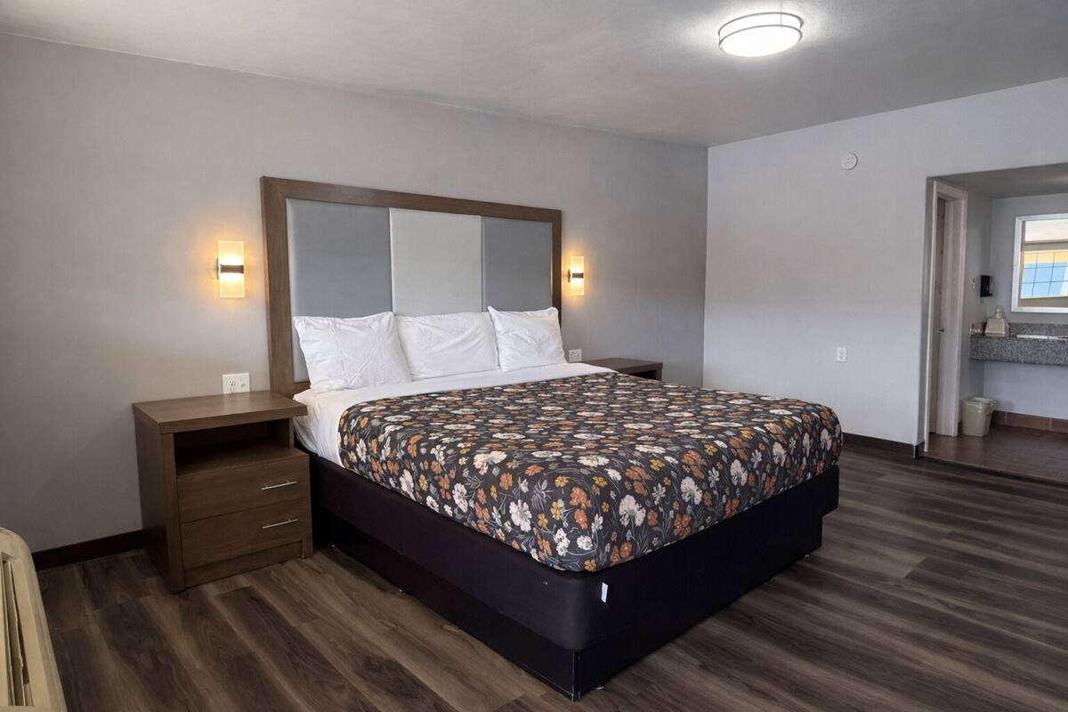 A modern bedroom with a large bed, bedside tables, and a built-in headboard.