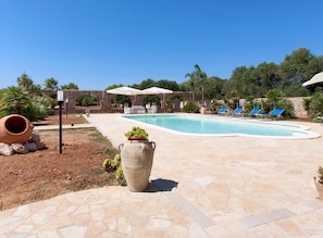 A pool area with stone flooring, lounge chairs, and umbrellas. - Casale Tre Petre (Galatone)