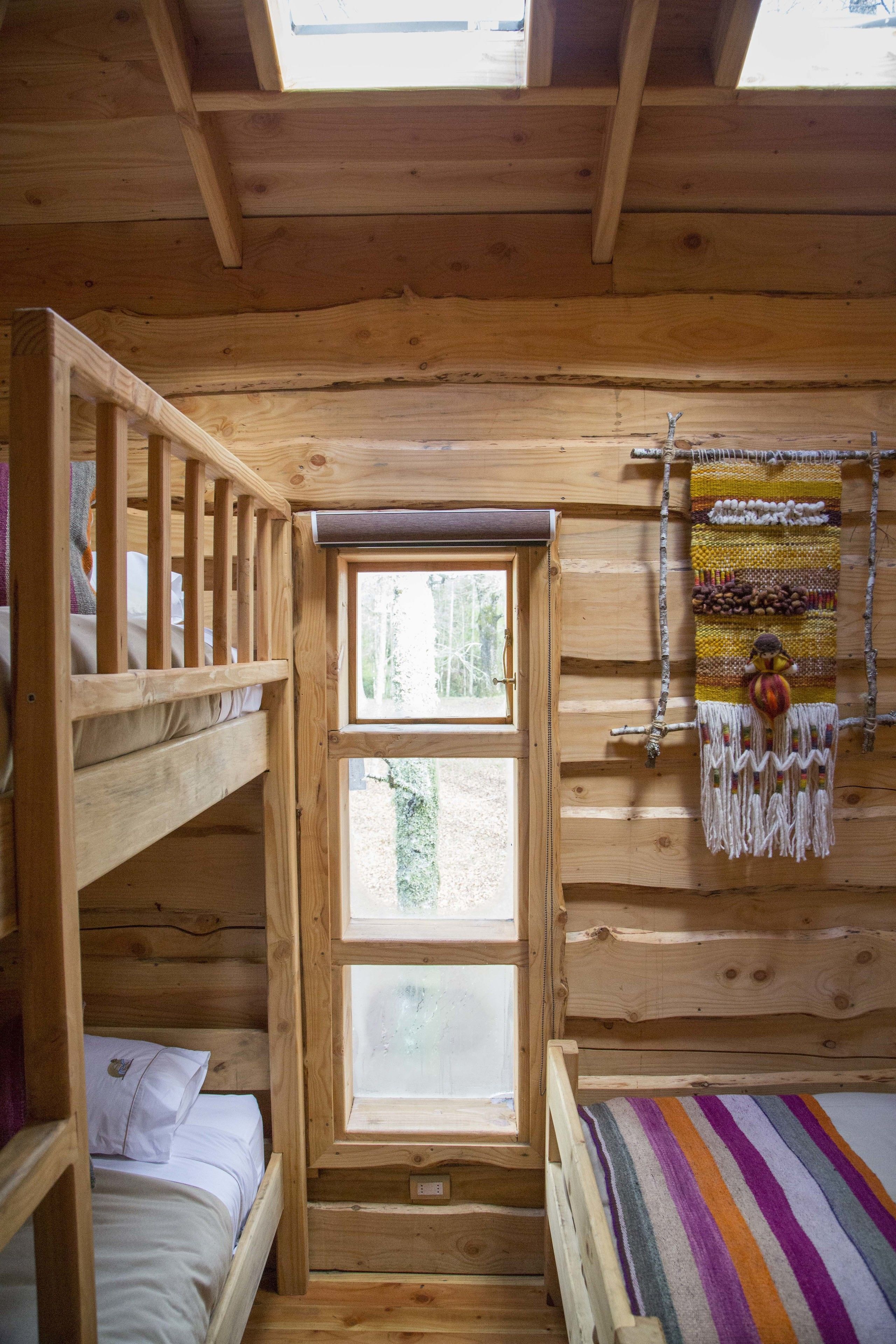Una habitación tipo cabaña con literas, un ventanal grande y un tapiz de pared colorido.