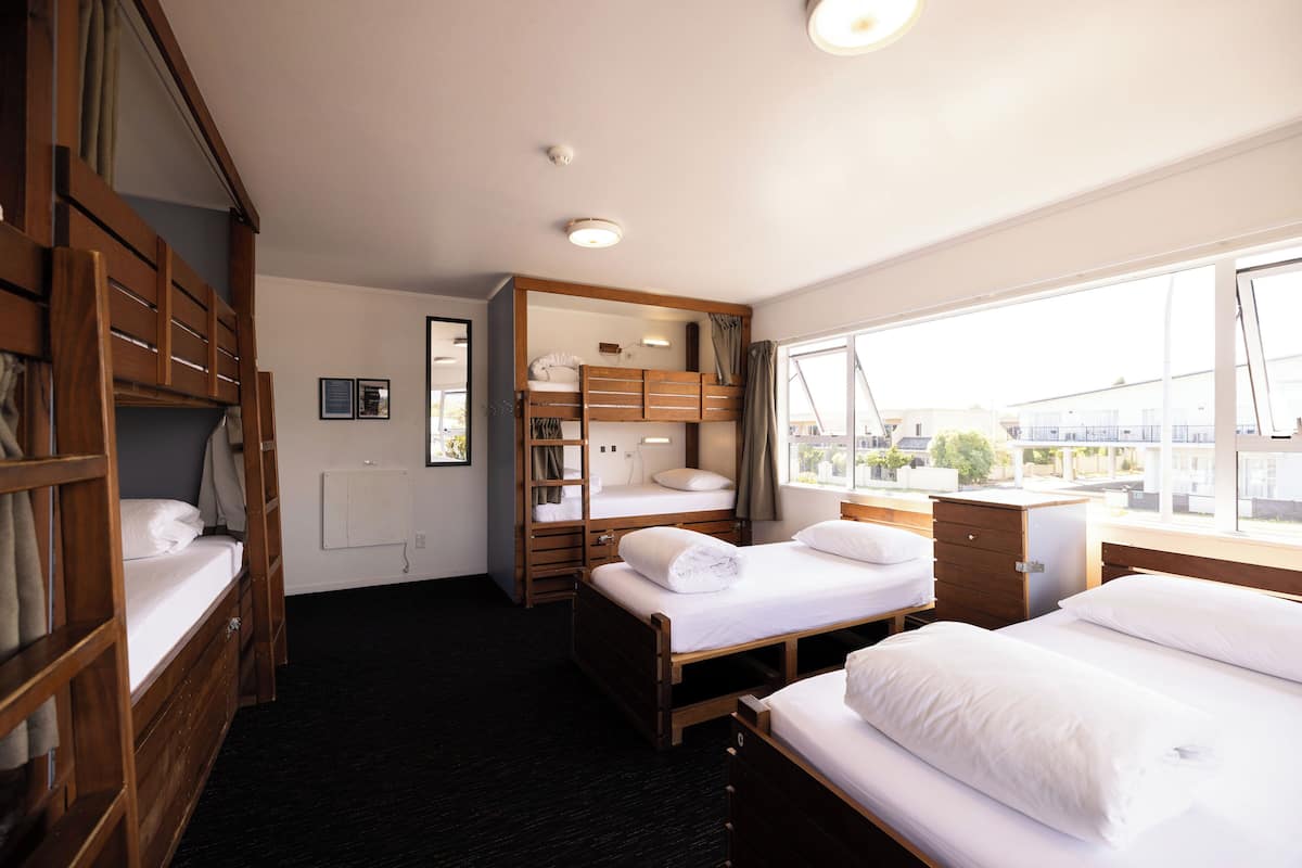 Ein Hotelzimmer mit Etagenbett, Schreibtisch und Fenster mit Blick auf die Stadt.