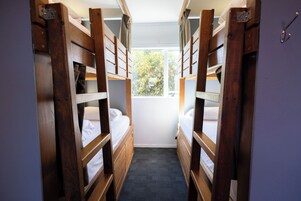 Una habitación pequeña con literas, una ventana y una puerta.