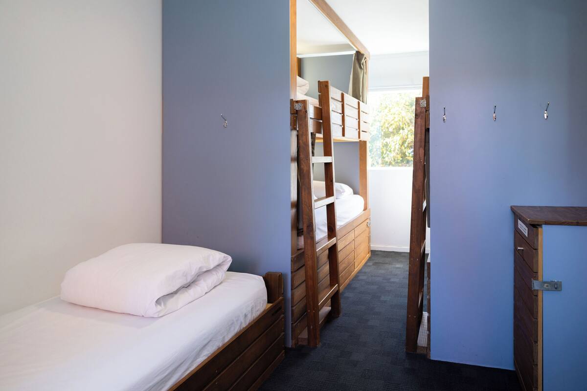 Ein Zimmer mit einem Etagenbett, einem Schreibtisch und einem Kleiderschrank.
