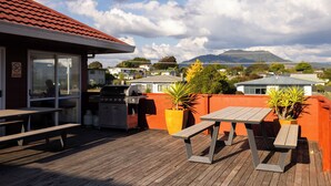Un patio al aire libre con mesas y bancos de madera, una parrilla y plantas en macetas.