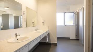 A clean, modern bathroom with two sinks, a large mirror, and a window providing natural light.