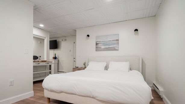 Un dormitorio moderno con una cama grande, un escritorio y una televisión en la pared.