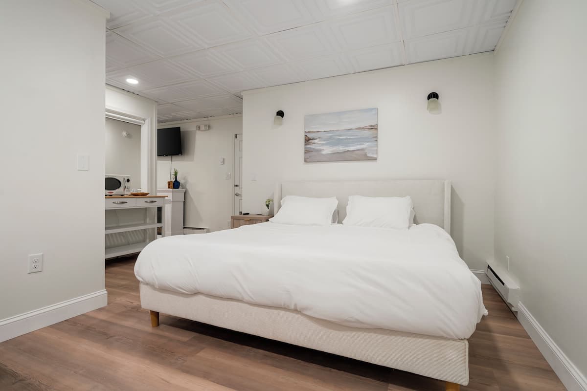 Une chambre moderne avec un grand lit, un bureau et un téléviseur fixé au mur.