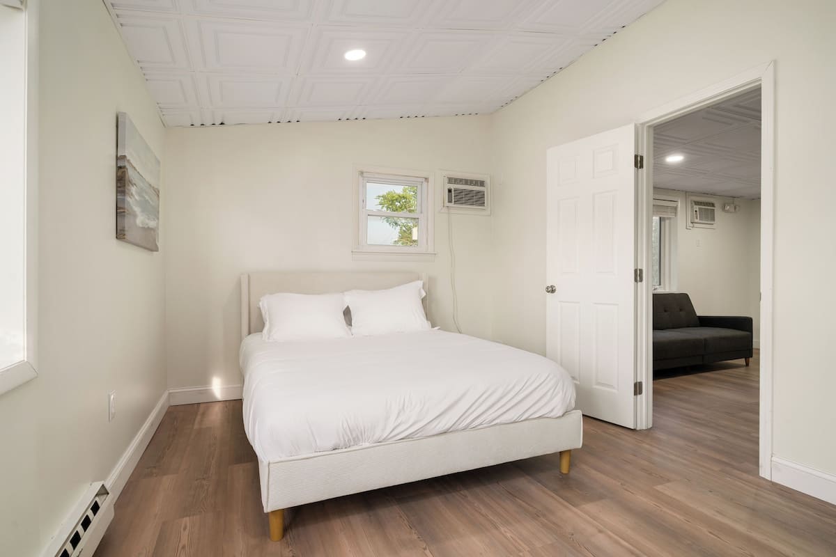 Une chambre à coucher avec un lit, une porte donnant sur une autre pièce et une fenêtre.