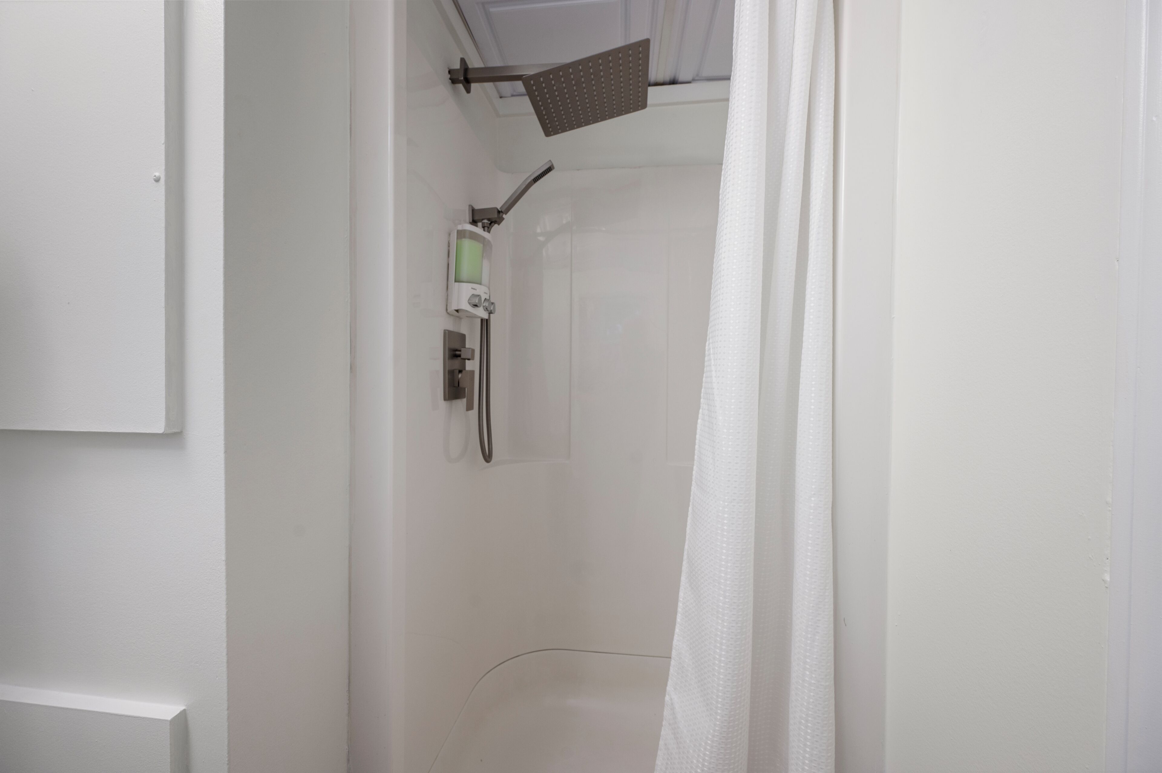 A white bathroom with a shower, a toilet, and a sink.