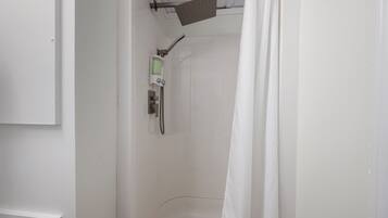A white bathroom with a shower, a toilet, and a sink.