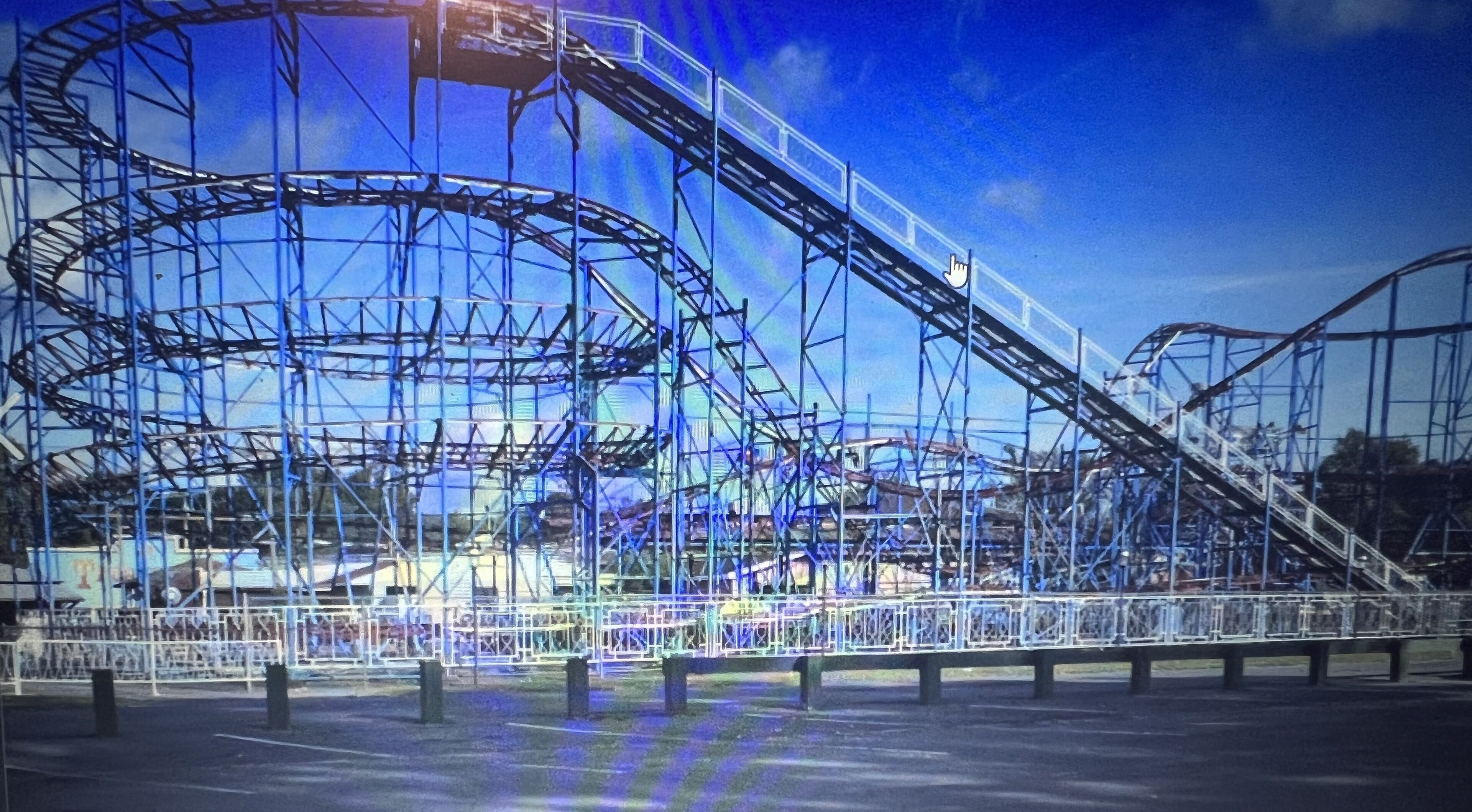 Eine Achterbahn mit komplexer Streckenführung, umgeben von Schutzvorrichtungen und blauem Himmel.