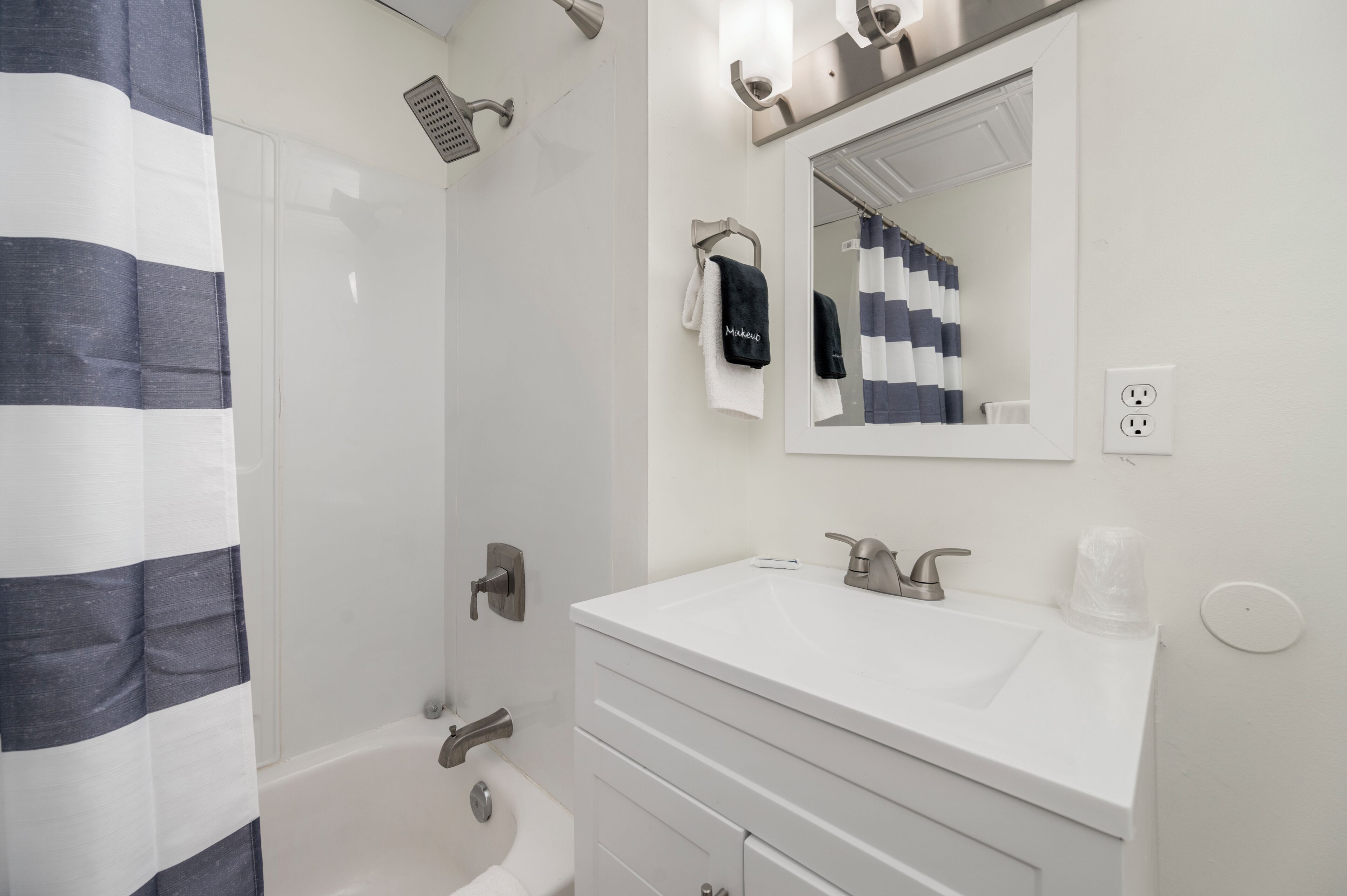 A modern bathroom with a white sink, mirror, and shower.