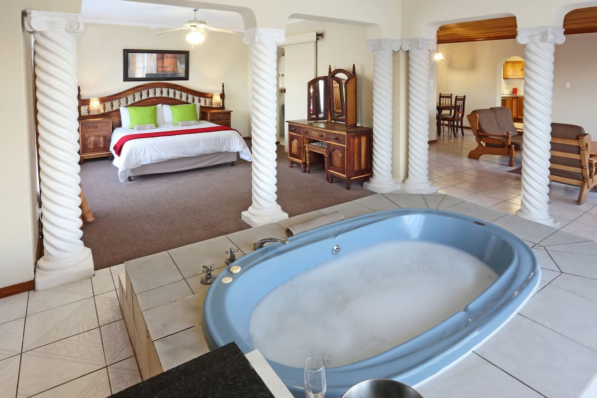 Un dormitorio con una cama grande, un aparador de madera, un espejo y una bañera azul.