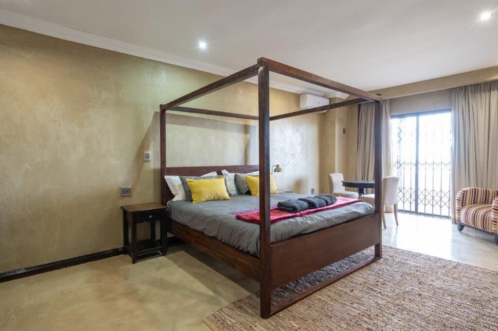 A four-poster bed in a room with a view to the outside.