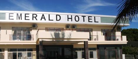The exterior of the Emerald Hotel with a clear sign, a two-story structure, and a covered entrance.
