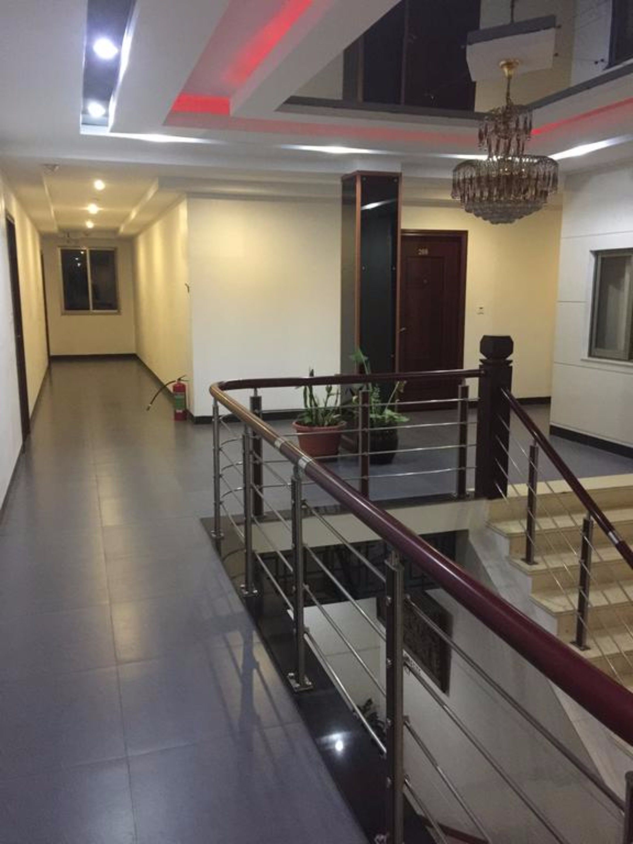 A spacious hallway with a staircase leading to an upper floor, a chandelier, and a potted plant.