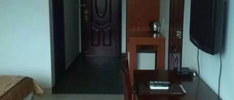 Una habitación de hotel con una cama, un escritorio, una silla, un televisor y una puerta.