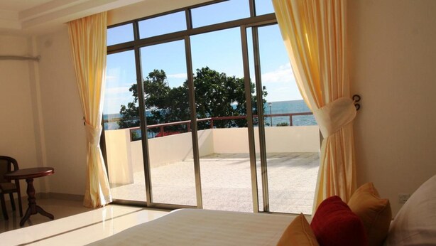 Habitació d'hotel amb un llit gran, vista a la platja i un balcó amb barana.