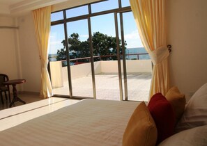 A hotel room with a large bed, a view of the beach, and a balcony with a railing. - Emerald Hotel (Nuku'alofa)