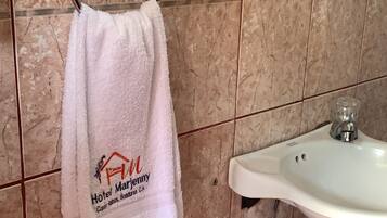 Un baño con un lavamanos blanco, una toalla colgada en un perchero metálico y un salpicadero decorativo de azulejos.