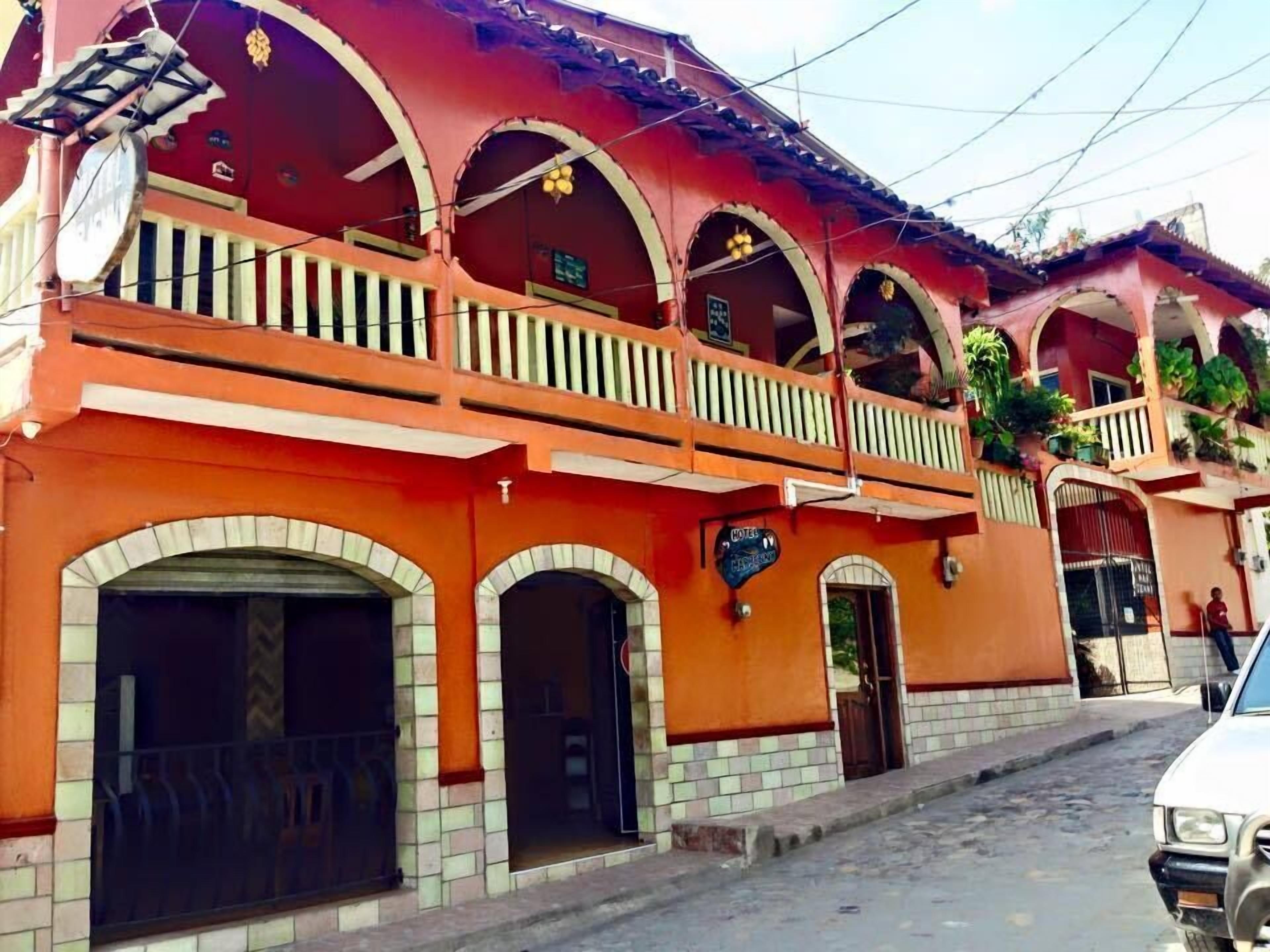 Un hotel con varios balcones, fachada con azulejos y un letrero que indica que es un hotel.