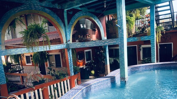 A swimming pool with tiled edges, surrounded by arches and potted plants. - Hotel Marjenny (Copan Ruinas)