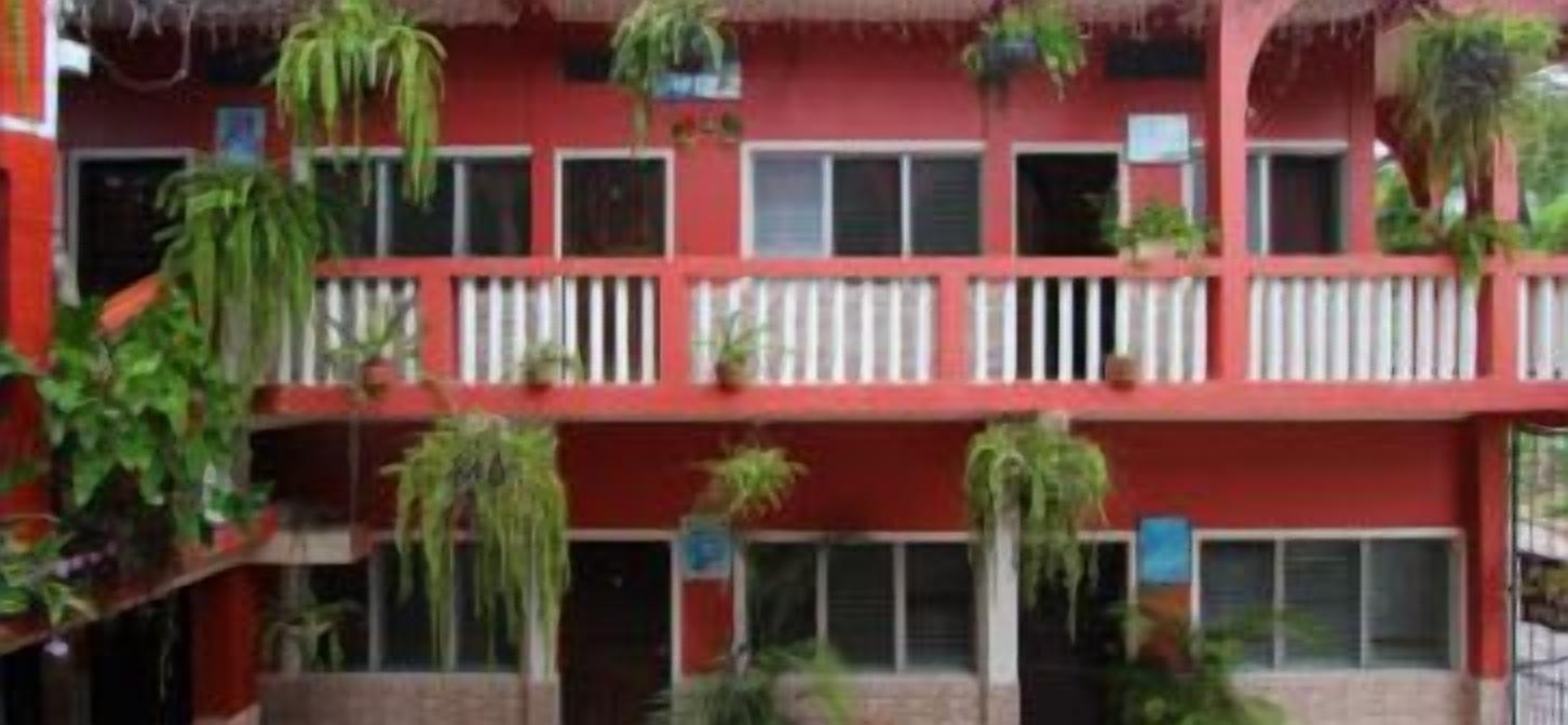 Un edificio rojo con varios balcones, algunos con plantas.