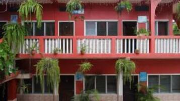 Un edificio rojo con varios balcones, algunos con plantas.