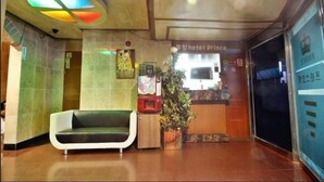 A hotel reception area with a green sofa, a plant, and a sign for 'Hotel Prince'. - Prince Motel (Gwangju)