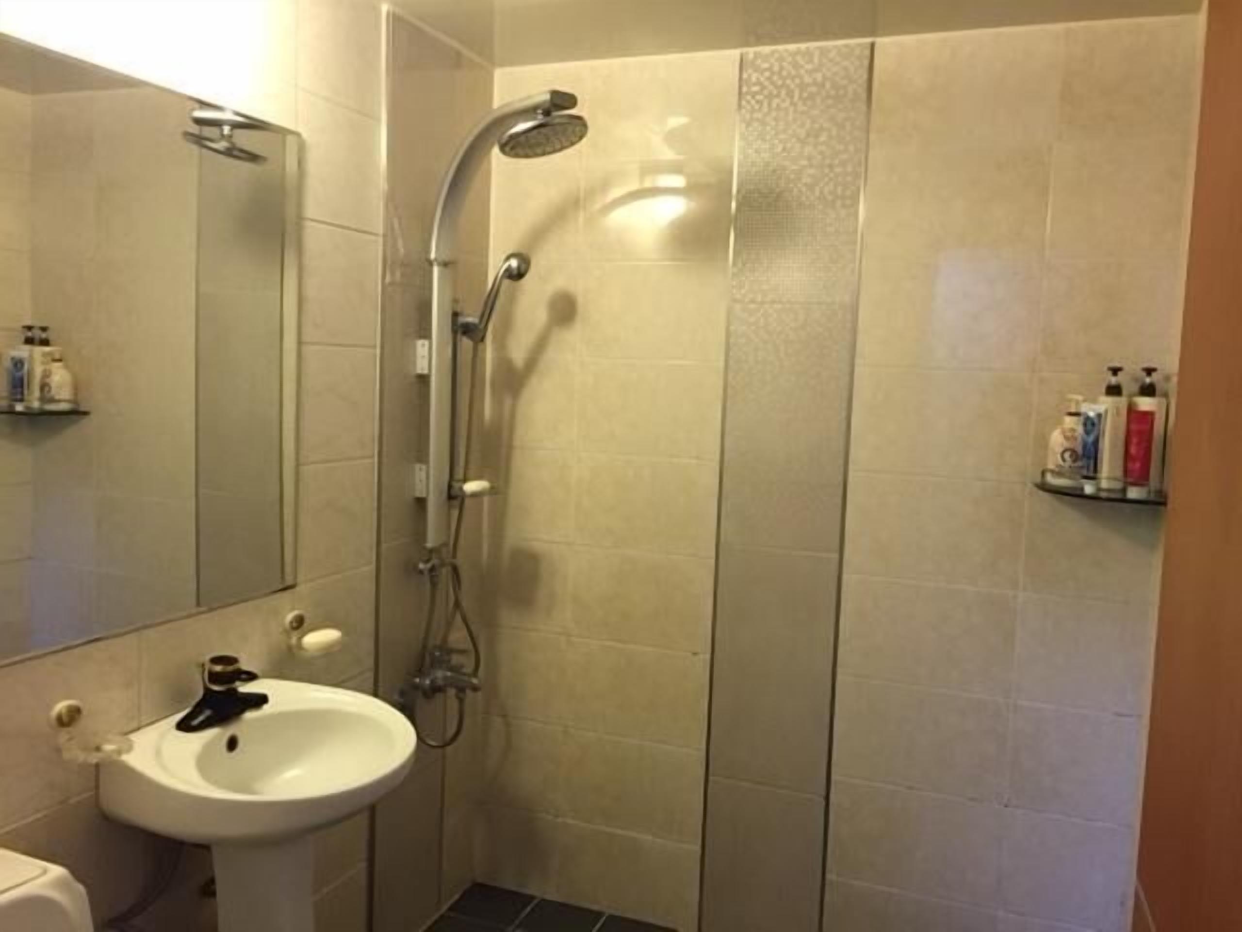 A bathroom with a shower, sink, and mirror.