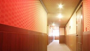 A narrow hallway with wooden walls and doors, leading to a bright room at the end. - Prince Motel (Gwangju)
