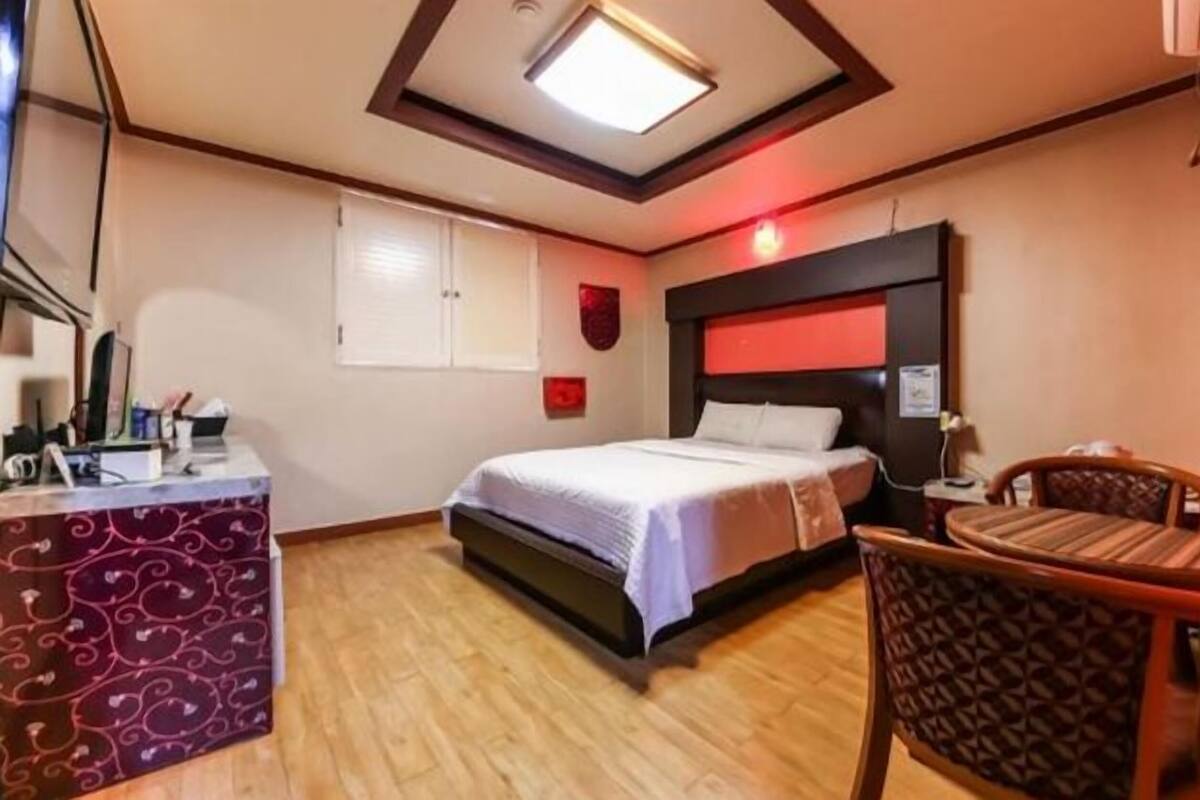 Una habitación de hotel con una cama, un escritorio con una computadora, una silla y una mesita.