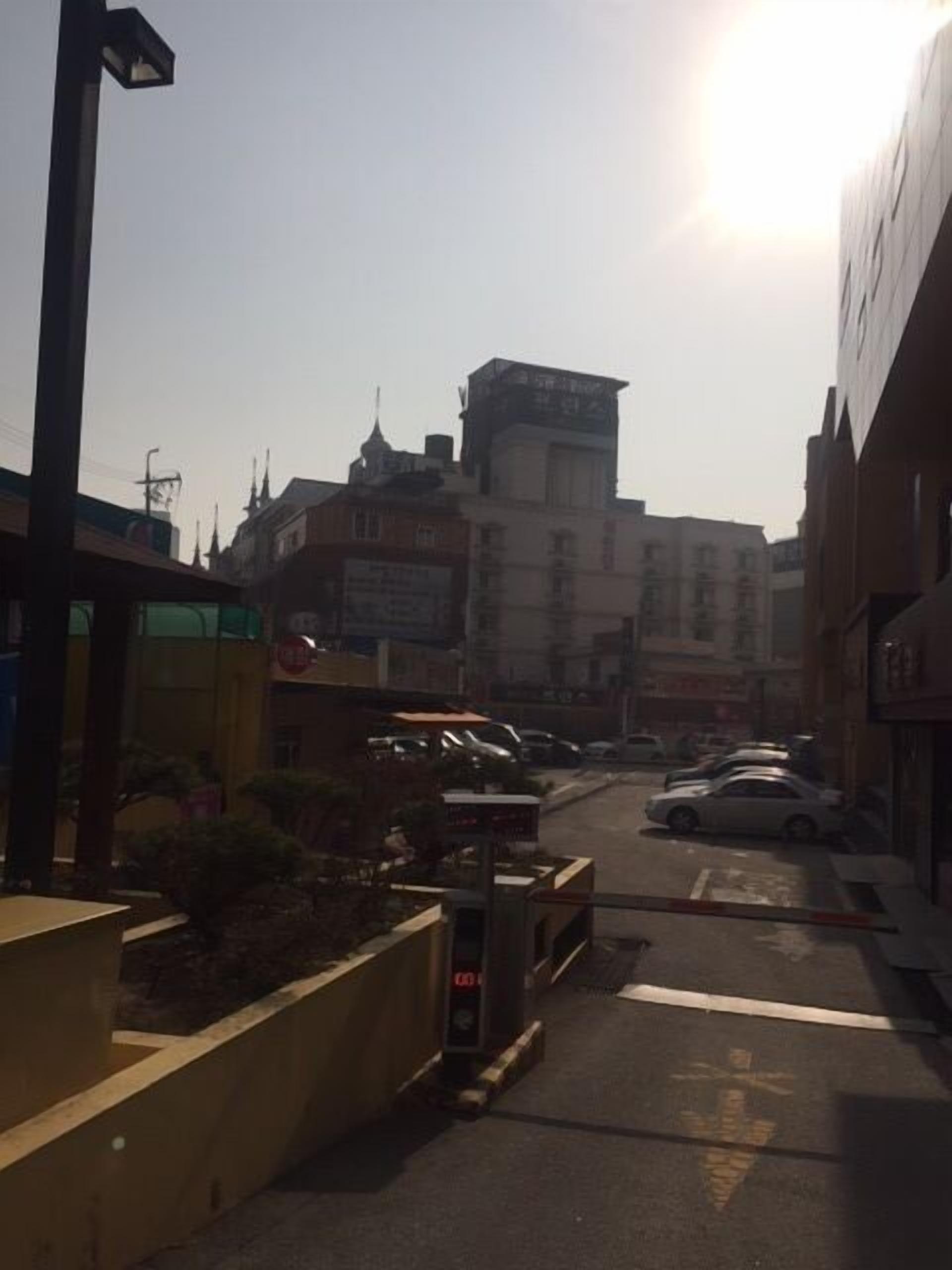 Vista de una calle con edificios, coches aparcados y cielo despejado.