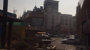 Vista de una calle con edificios, coches aparcados y cielo despejado.