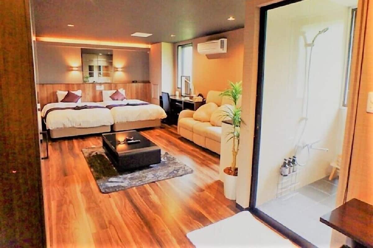 A modern bedroom with a double bed, a sofa, a coffee table, and a potted plant.