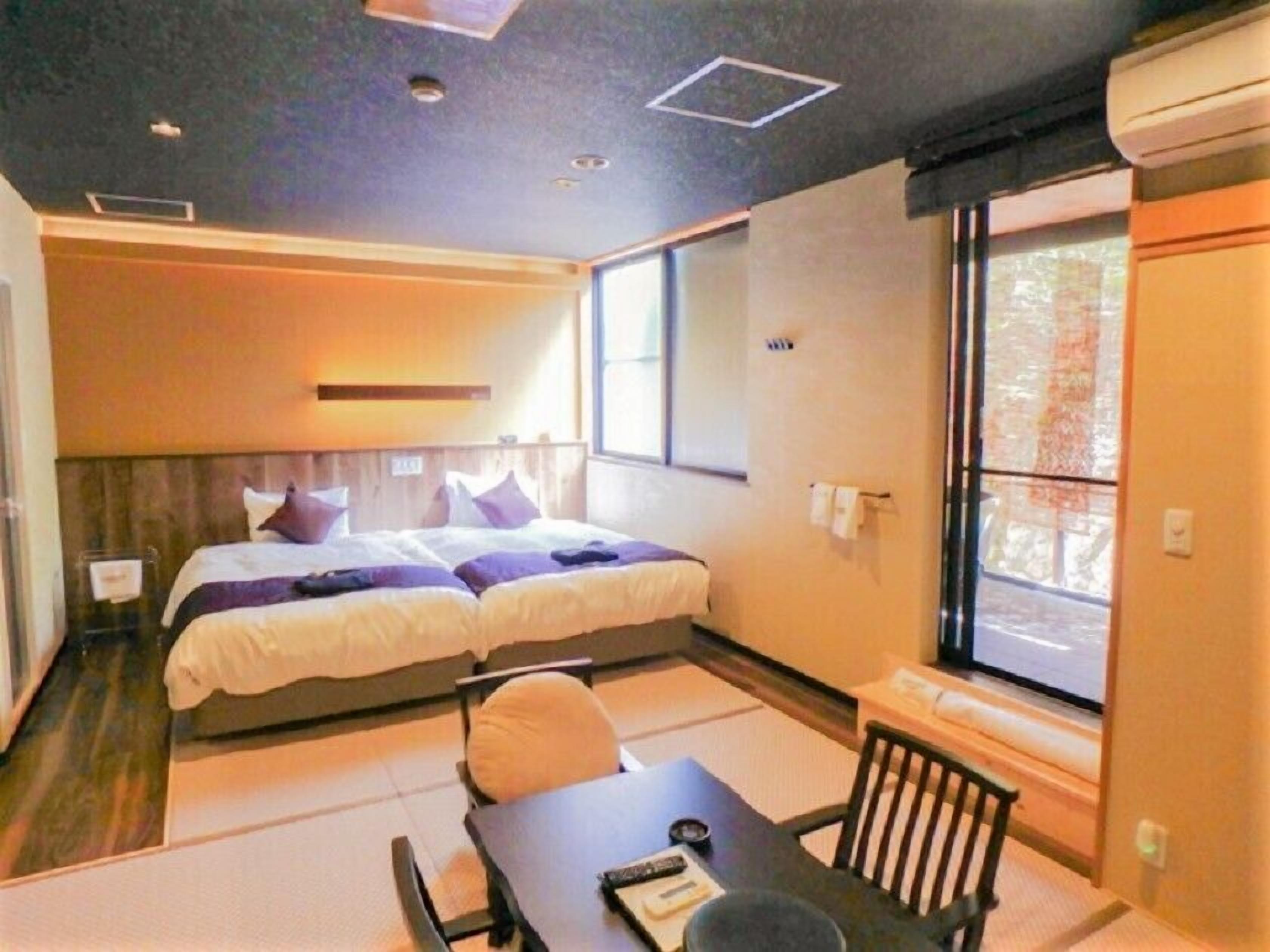 A hotel room with two beds, a small table, and a window.