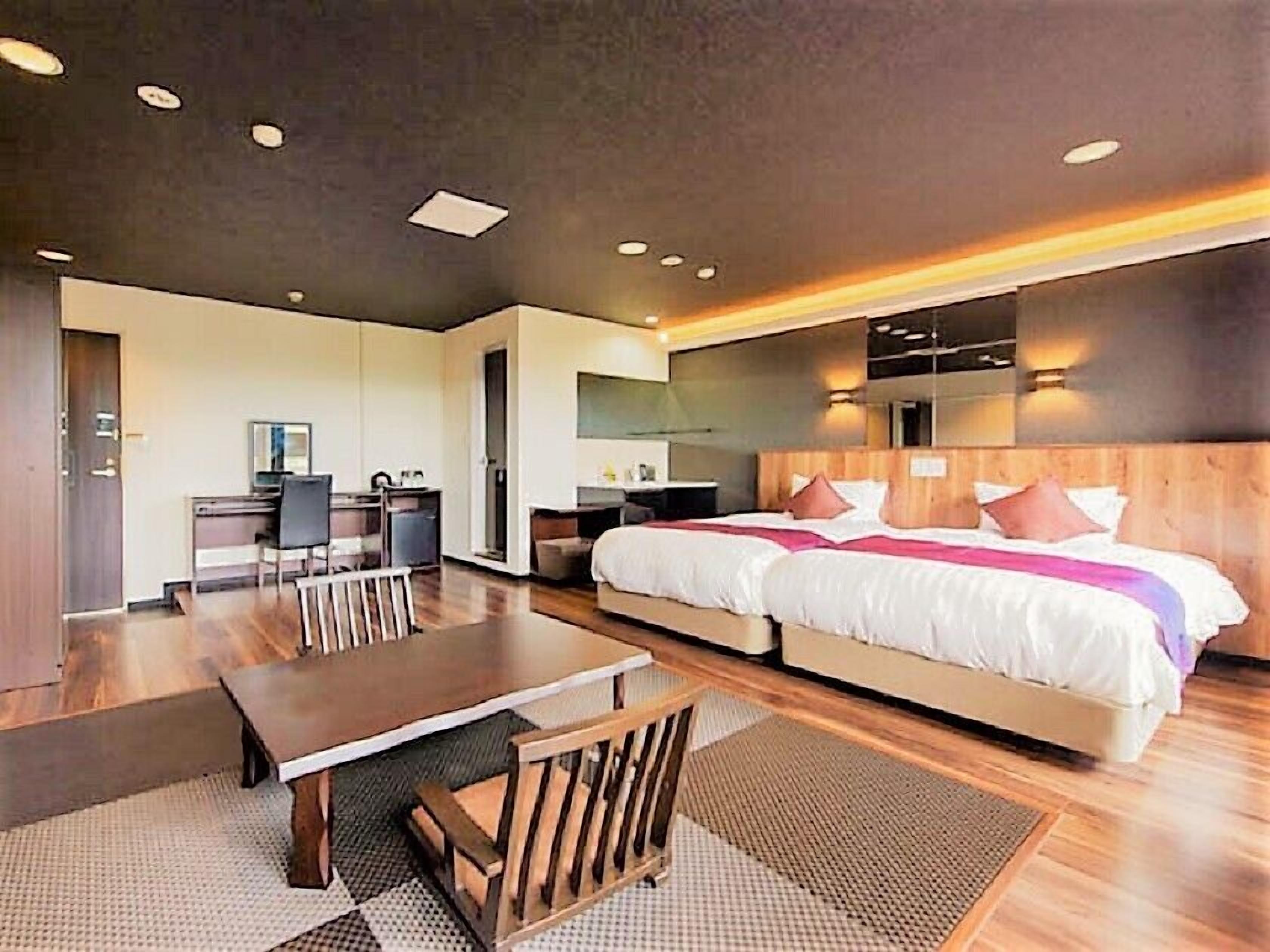 A modern hotel room with a large bed, a desk, and a seating area.