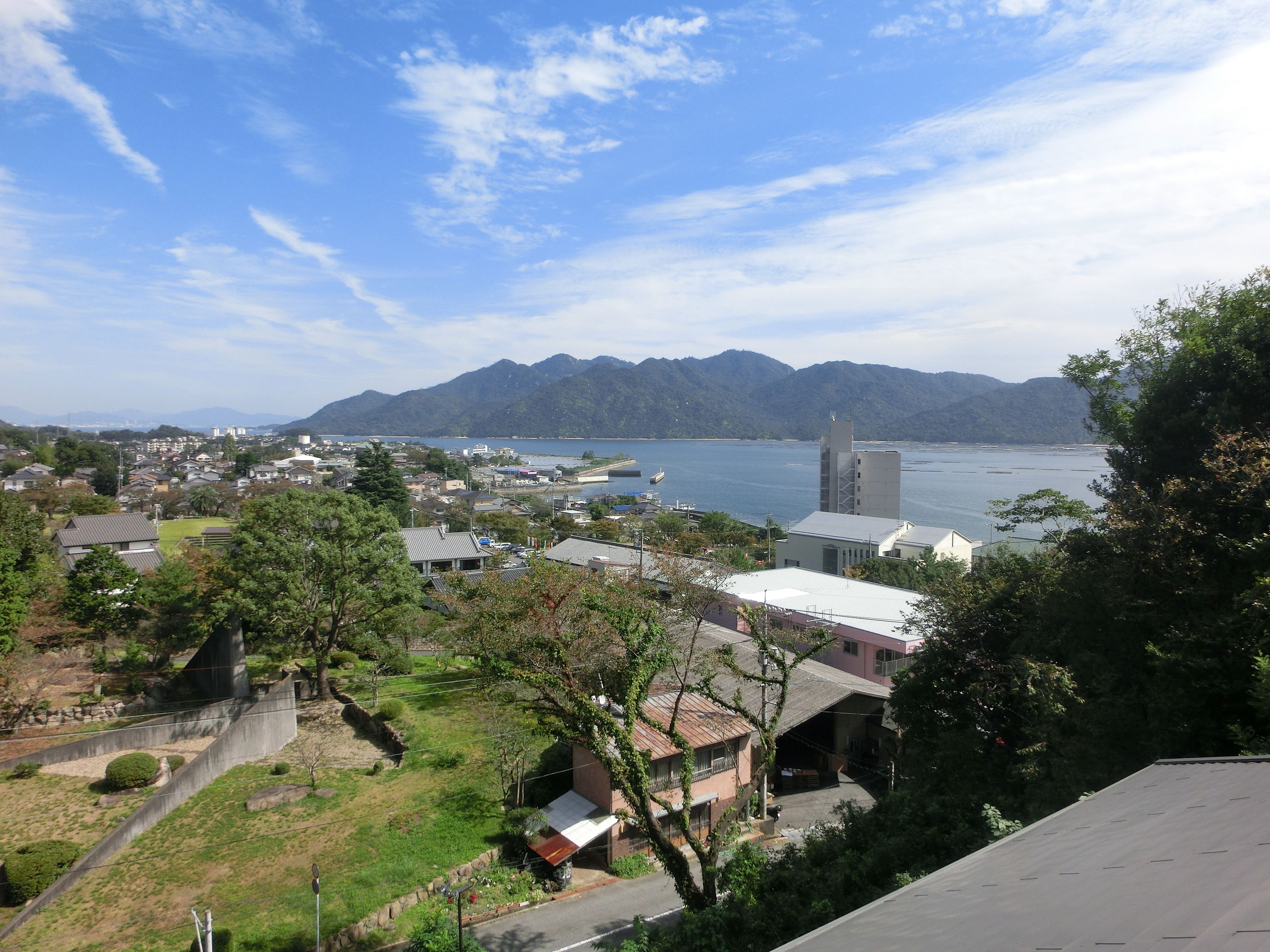 A coastal town with residential buildings, a church, and mountains in the background.