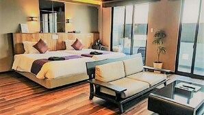 Een moderne hotelkamer met een groot bed, een bank, een salontafel en een potplant.