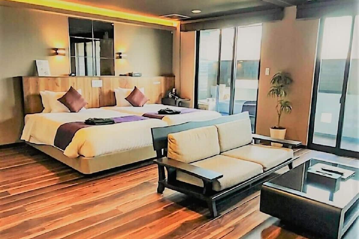 Een moderne hotelkamer met een groot bed, een bank, een salontafel en een potplant.