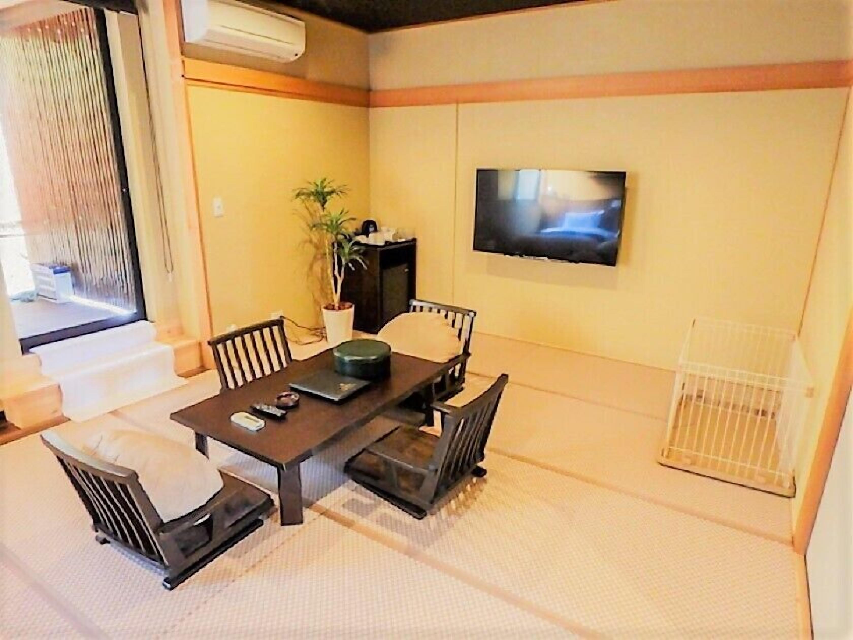 A dining area with a table, chairs, a TV, and a potted plant.