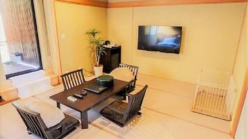 A dining area with a table, chairs, a TV, and a potted plant.